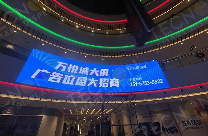 Transparent LED screen displays installed in a shopping mall showing vivid advertising visuals.